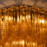 Ambleve Amber Glass Tube Flush Mount Chandelier | Fluted Amber Glass and Brass | Side close-up view of glowing amber glass tubes emitting warm light | Severn Lighting