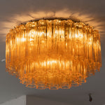 Ambleve Amber Glass Tube Flush Mount Chandelier | Fluted Amber Glass and Brass | Angled side view of the illuminated flush mount fixture on ceiling | Severn Lighting