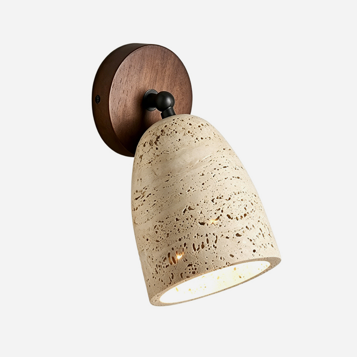 Aria Travertine Wood Wall Lamp | Travertine, Wood, Metal | Bell-shaped natural porous beige travertine shade with a round dark wood backplate and a black swivel joint | Isolated lit product shot on white background | Samu Lamp