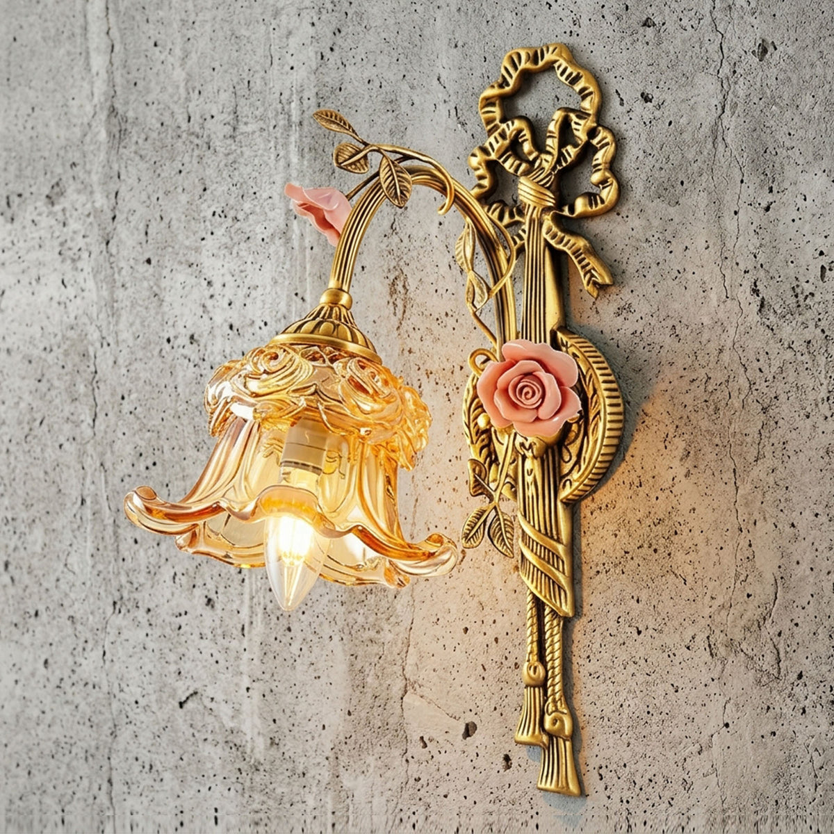 Armelle Rose Glass Brass Wall Lamp | Glass, Ceramic and Brass | Displayed illuminated against a rustic grey concrete wall | Severn Lighting