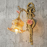Armelle Rose Glass Brass Wall Lamp | Glass, Ceramic and Brass | Displayed illuminated against a rustic grey concrete wall | Severn Lighting