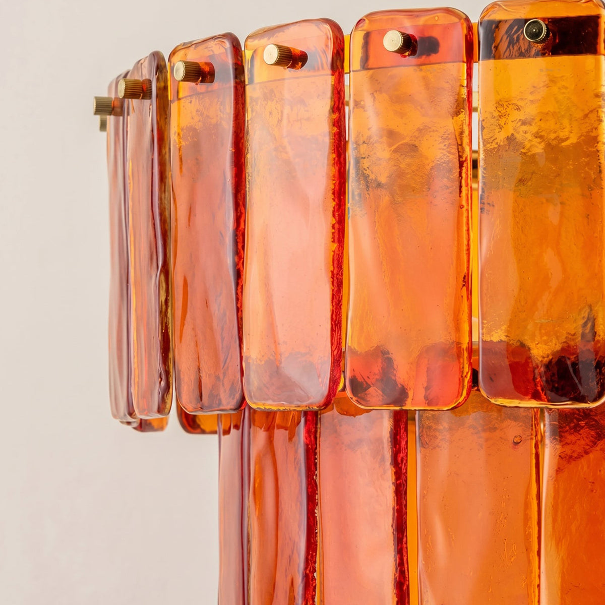 Aurelia Tiered Amber Glass Chandelier | Glass, Metal | Close-up side profile highlighting the smooth rounded edges and vibrant glossy translucent texture of the amber orange glass slats | Detail shot | Severn Lighting