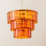 Aurelia Tiered Amber Glass Chandelier | Glass, Metal | Studio front view of the fully illuminated three-tier amber glass fixture casting a warm golden light against a plain cream backdrop | Severn Lighting