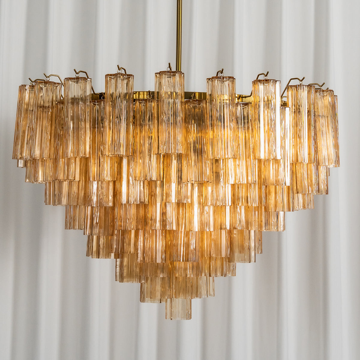 Auriane Fluted Amber Glass Chandelier | Fluted Amber Glass and Brass | Front full shot displayed against a vertical fluted wall panel | Severn Lighting