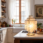 Callista Tiered Capiz Table Lamp | Capiz, Metal | Staged gracefully on a modern white kitchen island counter with wooden accents and window views | Severn Lighting