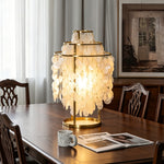 Callista Tiered Capiz Table Lamp | Capiz, Metal | Casting a welcoming glow as a decorative centerpiece on a long dark wood dining table with high-back matching chairs | Severn Lighting