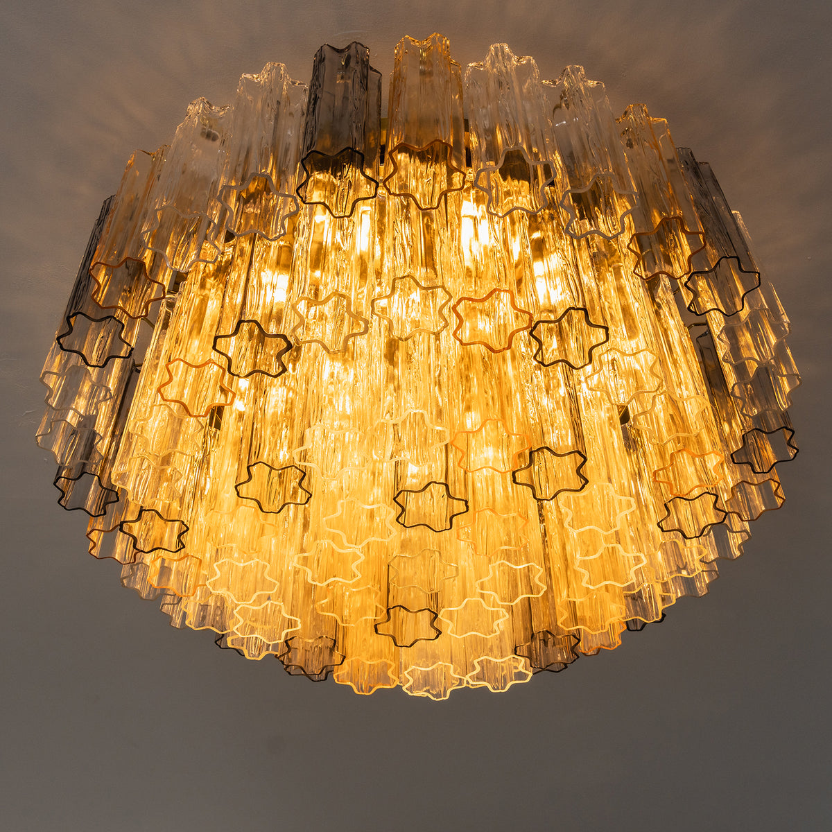 Cassian Tiered Fluted Glass Ceiling Light | Tiered Fluted Glass and Gold Brass | Low-angle studio perspective shot fully lit with warm golden light emphasizing the tiered layers | Severn Lighting