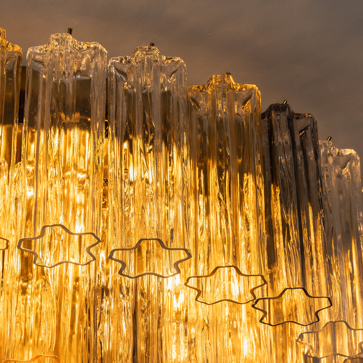Cassian Tiered Fluted Glass Ceiling Light | Tiered Fluted Glass and Gold Brass | Macro close-up texture shot focusing on the golden light filtering through the fluted glass prisms | Severn Lighting