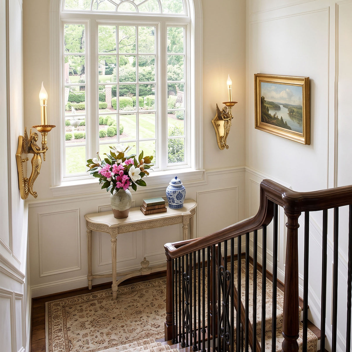 Clemency Winged Figure Brass Sconce | Cast Brass and Glass | Mounted on a hallway wall near a wooden staircase and console table | Severn Lighting