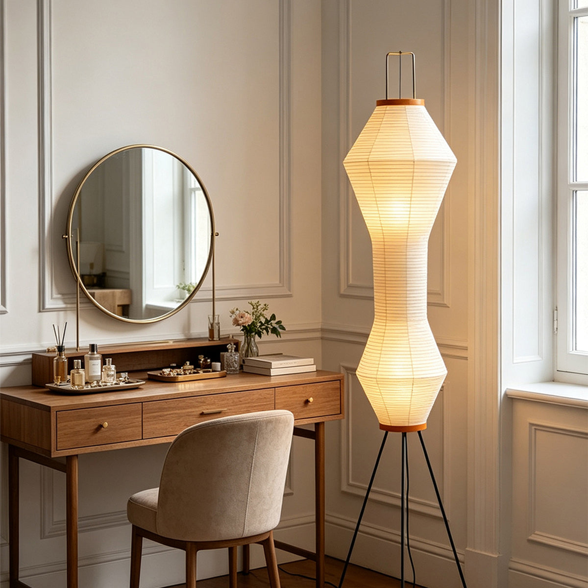 Cosima Hourglass Washi Paper Floor Lamp | Japanese Wabi-Sabi Paper and Black Tripod | Standing in a chic dressing corner beside a wooden vanity desk and a round mirror | Severn Lighting