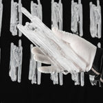 Ethereal Icicle Waterfall Chandelier | Frosted Icicle Glass and Gold Brass | A gloved hand holding a bundle of unlit textured white icicle glass rod components over a dark surface | Severn Lighting