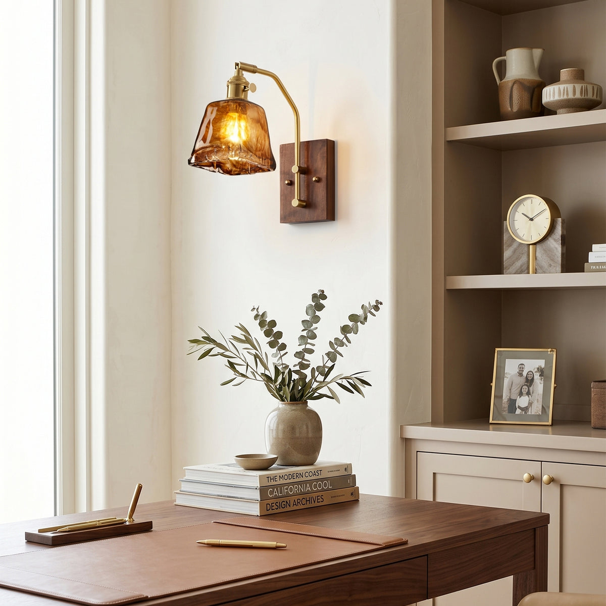 Everett Amber Ripple Wall Sconce | Amber Rippled Glass and Walnut Wood | Fixed on a home office wall casting light over a wooden desk with a built-in shelf | Severn Lighting