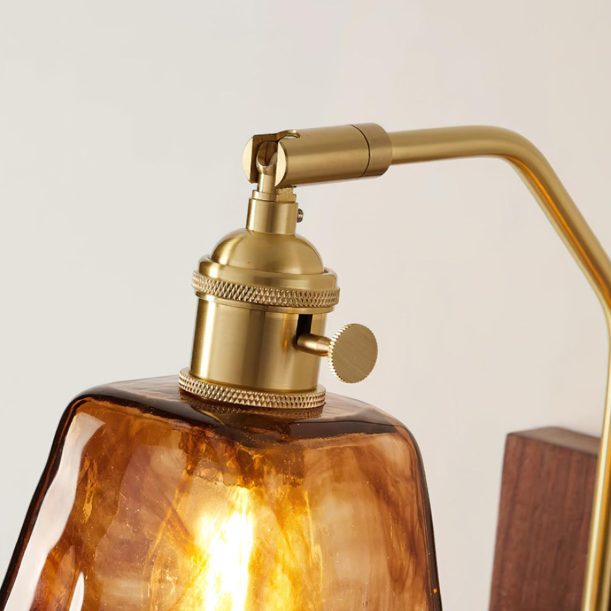 Everett Amber Ripple Wall Sconce | Amber Rippled Glass and Walnut Wood | Close-up detail view of the polished brass hardware socket atop the rippled glass shade | Severn Lighting