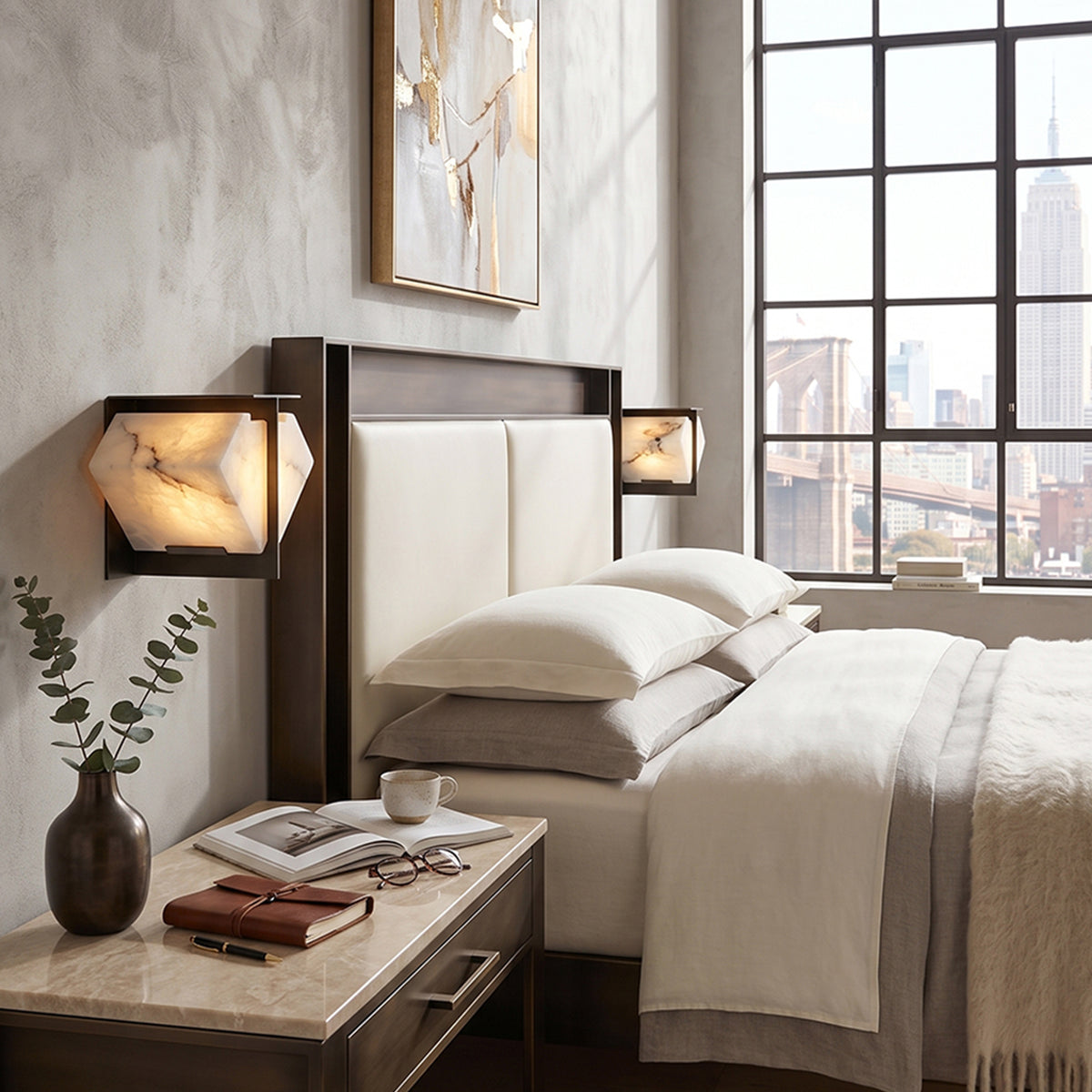 Freya Angular Alabaster Wall Sconce | Bedside Accent Light | Staged as an elegant bedside reading light casting a warm golden glow next to a platform bed in an industrial loft bedroom | Severn Lighting