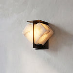 Freya Angular Alabaster Wall Sconce | Texture Detail Shot | Side angle profile view of the lit geometric stone wall lamp showcasing its organic mineral texture on a grey plaster wall | Severn Lighting