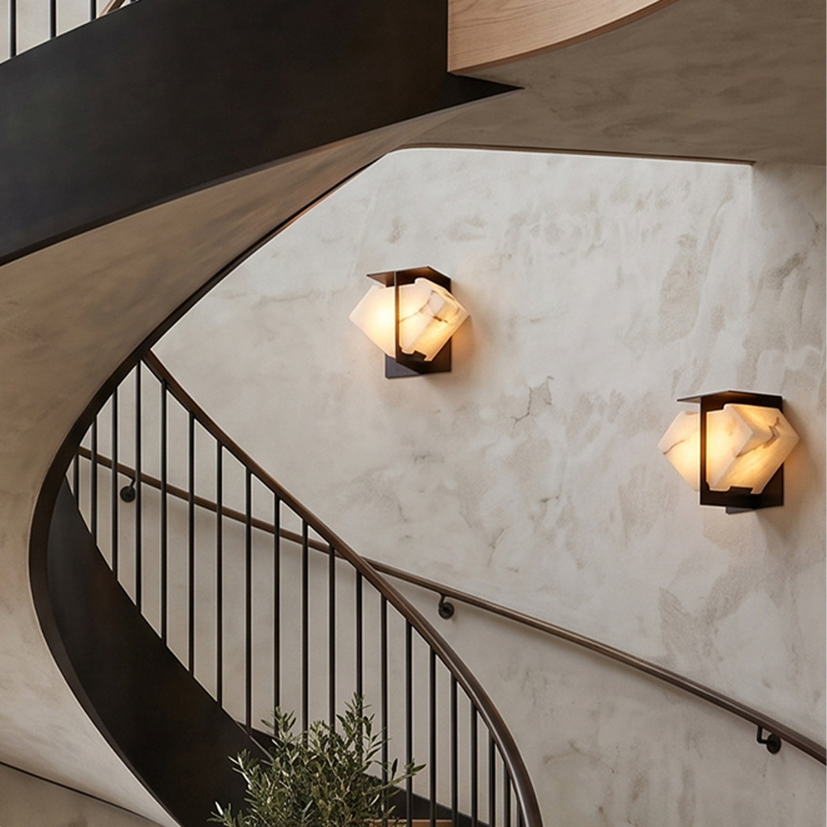 Freya Angular Alabaster Wall Sconce | Staircase Wall Sconces | Two illuminated architectural wall lamps mounted along a dramatic curved concrete spiral staircase wall | Severn Lighting