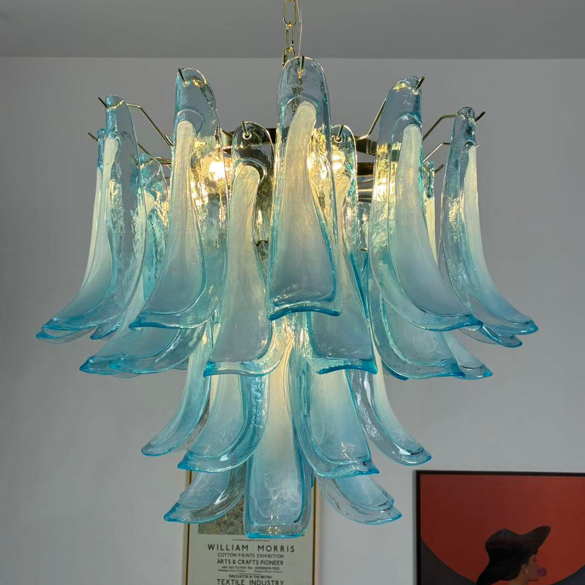 Isar Blue Petal Glass Chandelier | Blue Glass and Brass | Real-life installation view glowing brightly near wall artwork | Severn Lighting