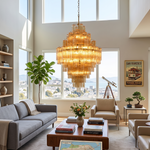 Kester Amber Glass Tier Chandelier | Amber Glass and Brass | Suspended in a high-ceiling living room with a grey sofa | Severn Lighting