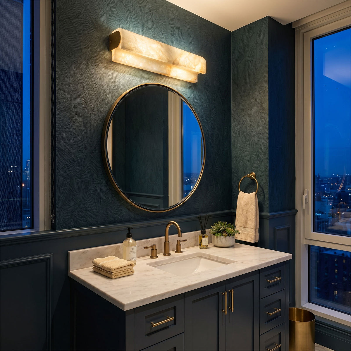 Lamelune Stacked Sconce | Alabaster and Brass | Lit above circular mirror in a navy blue luxury bathroom | Severn Lighting