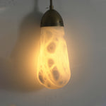 Larmelle Teardrop Sconce | Alabaster and Brass | Front illuminated view suspended against plaster wall | Severn Lighting