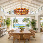 Lovenne Textured Glass Disc Ring Chandelier | Textured Glass and Brass | Amber variant illuminated above a long dining table near oceanfront glass doors | Severn Lighting