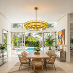 Lovenne Textured Glass Disc Ring Chandelier | Textured Glass and Brass | Displayed in a bright dining area above a round table facing a poolside garden | Severn Lighting