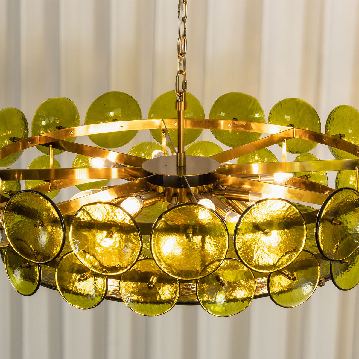 Lovenne Textured Glass Disc Ring Chandelier | Textured Glass and Brass | Close-up view of the green glass disc chandelier against a striped backdrop | Severn Lighting