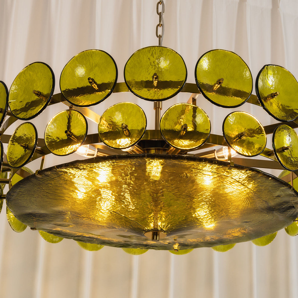 Lovenne Textured Glass Disc Ring Chandelier | Textured Glass and Brass | Front angled product view of the green glass chandelier illuminated warmly | Severn Lighting