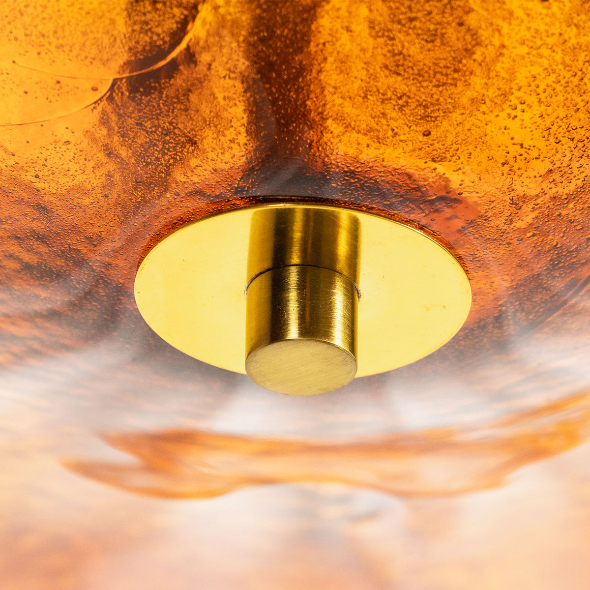 Lovenne Textured Glass Disc Ring Chandelier | Textured Glass and Brass | Macro detail shot of the brass bottom finial and amber glass diffuser disc | Severn Lighting