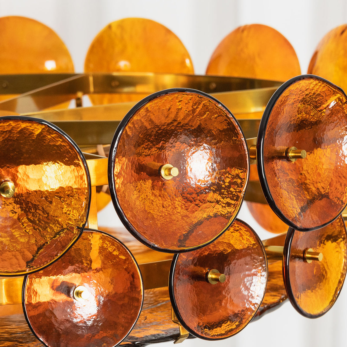 Lovenne Textured Glass Disc Ring Chandelier | Textured Glass and Brass | Close-up view of the layered amber textured glass discs glowing with warm light | Severn Lighting