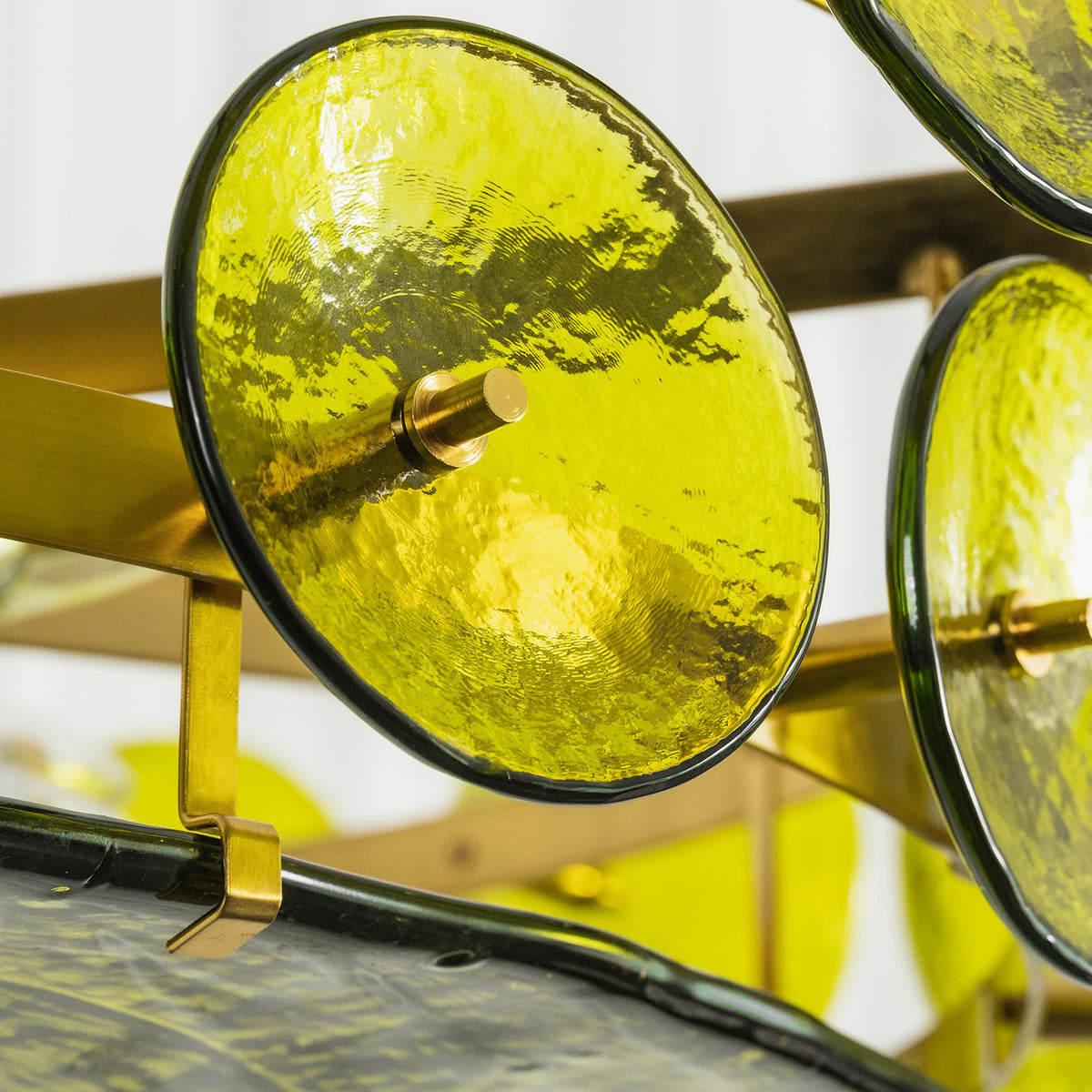 Lovenne Textured Glass Disc Ring Chandelier | Textured Glass and Brass | Macro close-up shot of a green textured glass disc secured by brass hardware | Severn Lighting