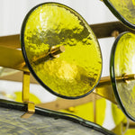 Lovenne Textured Glass Disc Ring Chandelier | Textured Glass and Brass | Macro close-up shot of a green textured glass disc secured by brass hardware | Severn Lighting