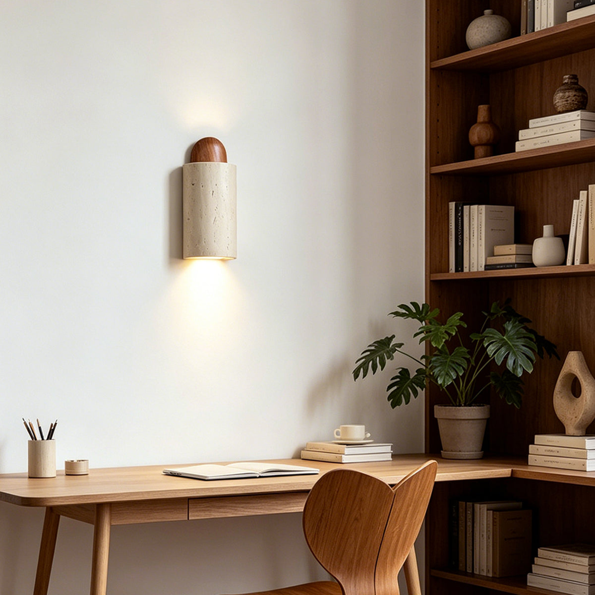 Lyra Travertine Shield Wall Lamp | Travertine, Wood, Metal | Mounted as a sleek downlight over a light wood writing desk and matching chair in a modern home office with bookshelves | Severn Lighting