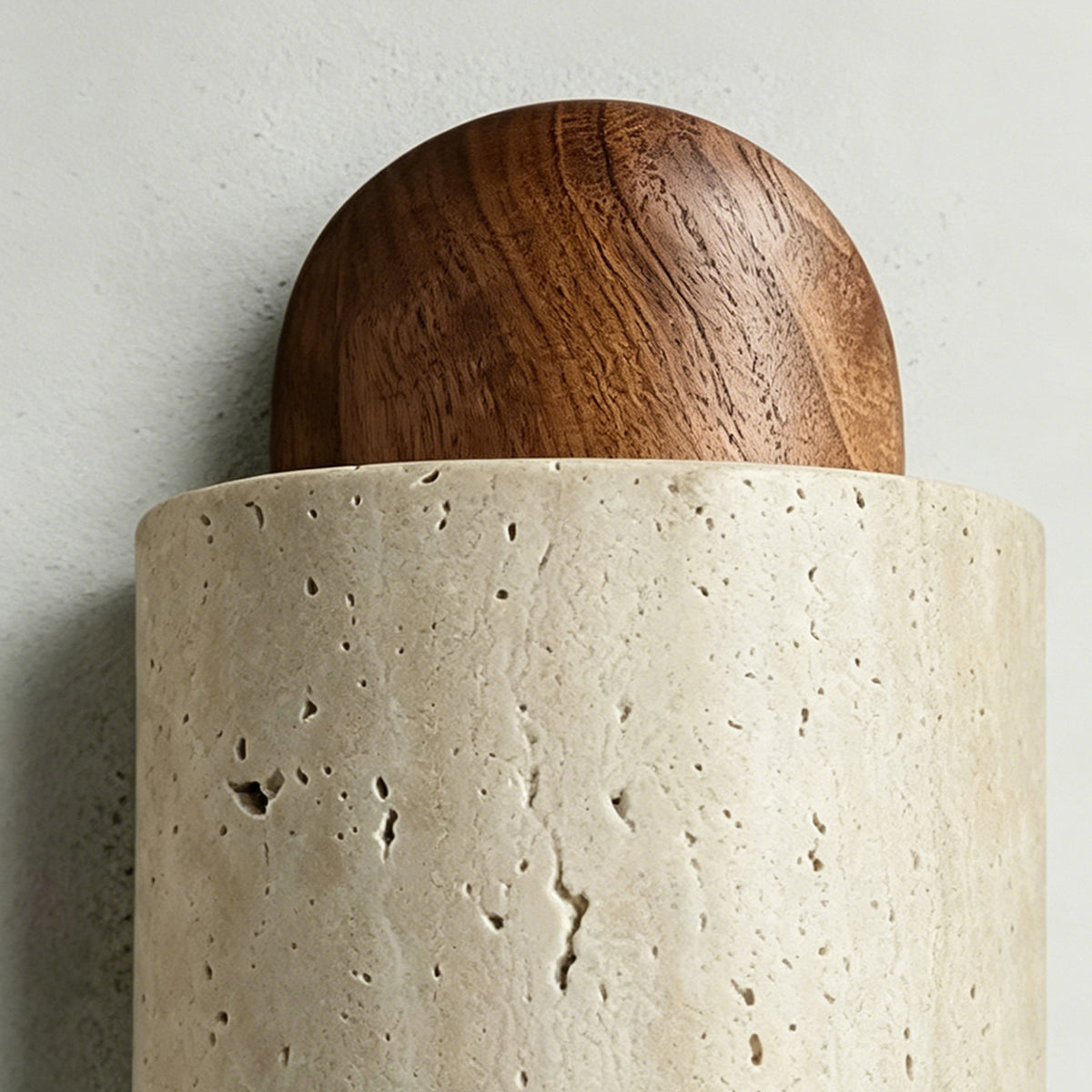 Lyra Travertine Shield Wall Lamp | Travertine, Wood, Metal | Macro close-up showcasing the contrast between the smooth polished walnut wood dome and porous beige travertine stone | Detail shot | Severn Lighting