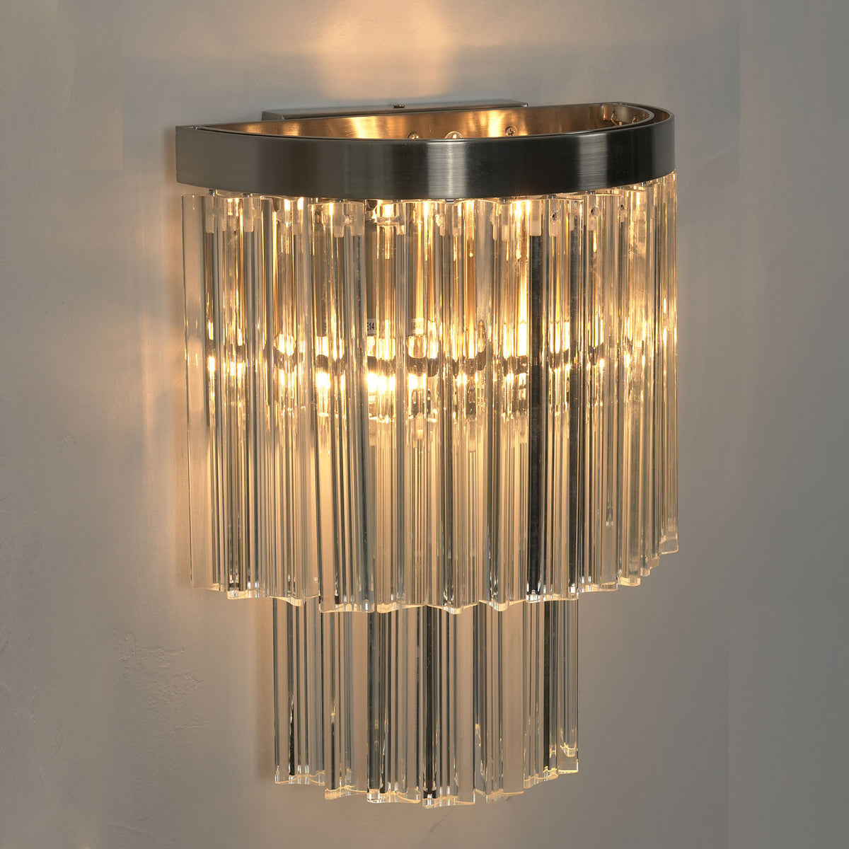 Marelle Glass Rod Tiered Wall Lamp | Clear Glass Rods and Metal | Studio product view glowing brightly displayed against a plain background | Severn Lighting