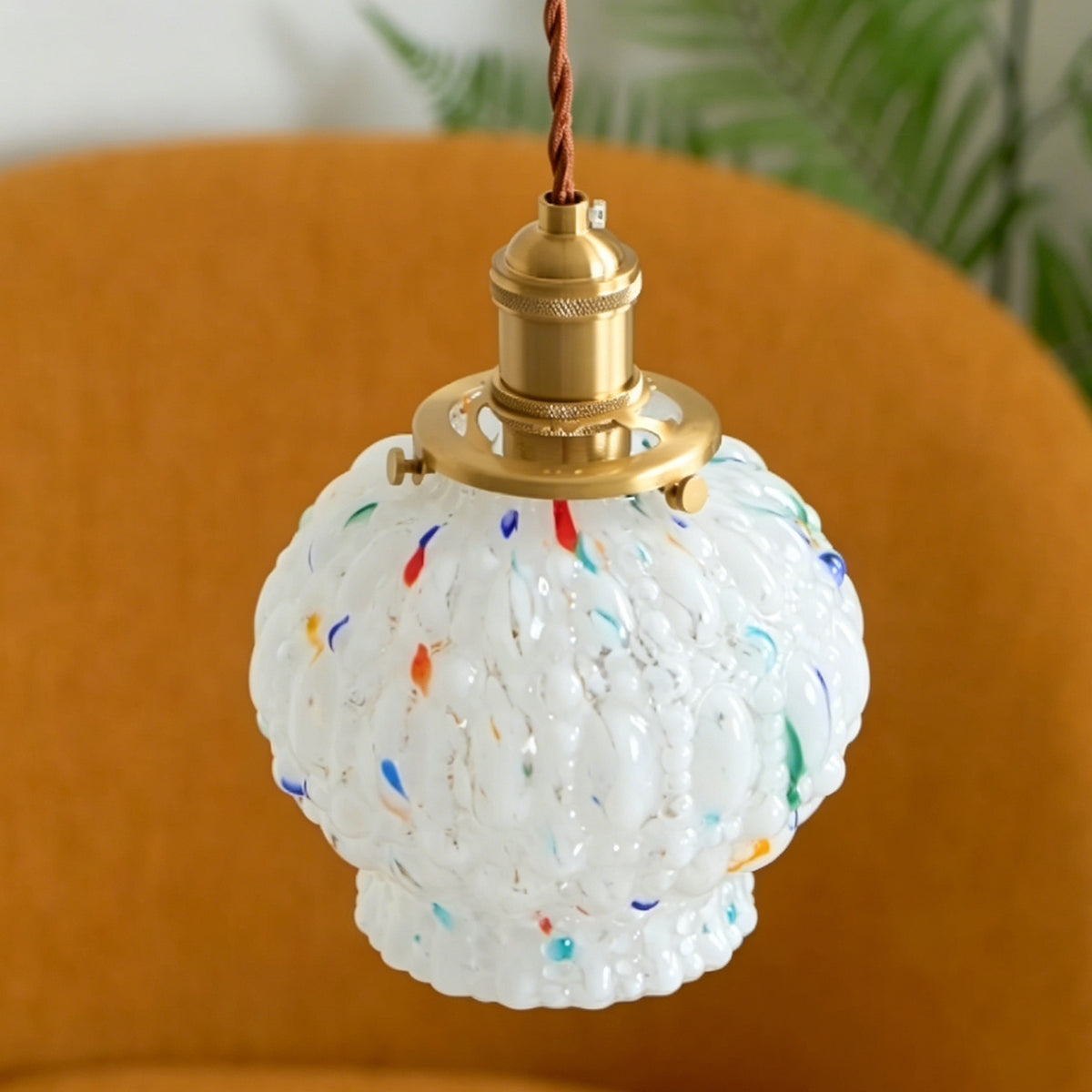 Marlowe Speckled Glass Pendant Lamp | Colorful Speckled Glass and Brass | Standard unlit product view hanging in front of a warm orange velvet round chair | Severn Lighting