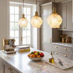 Marlowe Speckled Glass Pendant Lamp | Colorful Speckled Glass and Brass | A row of three lit glass pendants illuminating a modern kitchen island with white cabinets | Severn Lighting