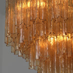 Merlande Amber Glass Tube Tiered Chandelier | Fluted Amber Glass and Brass | Close-up view of cascading amber glass tubes glowing with warm light | Severn Lighting