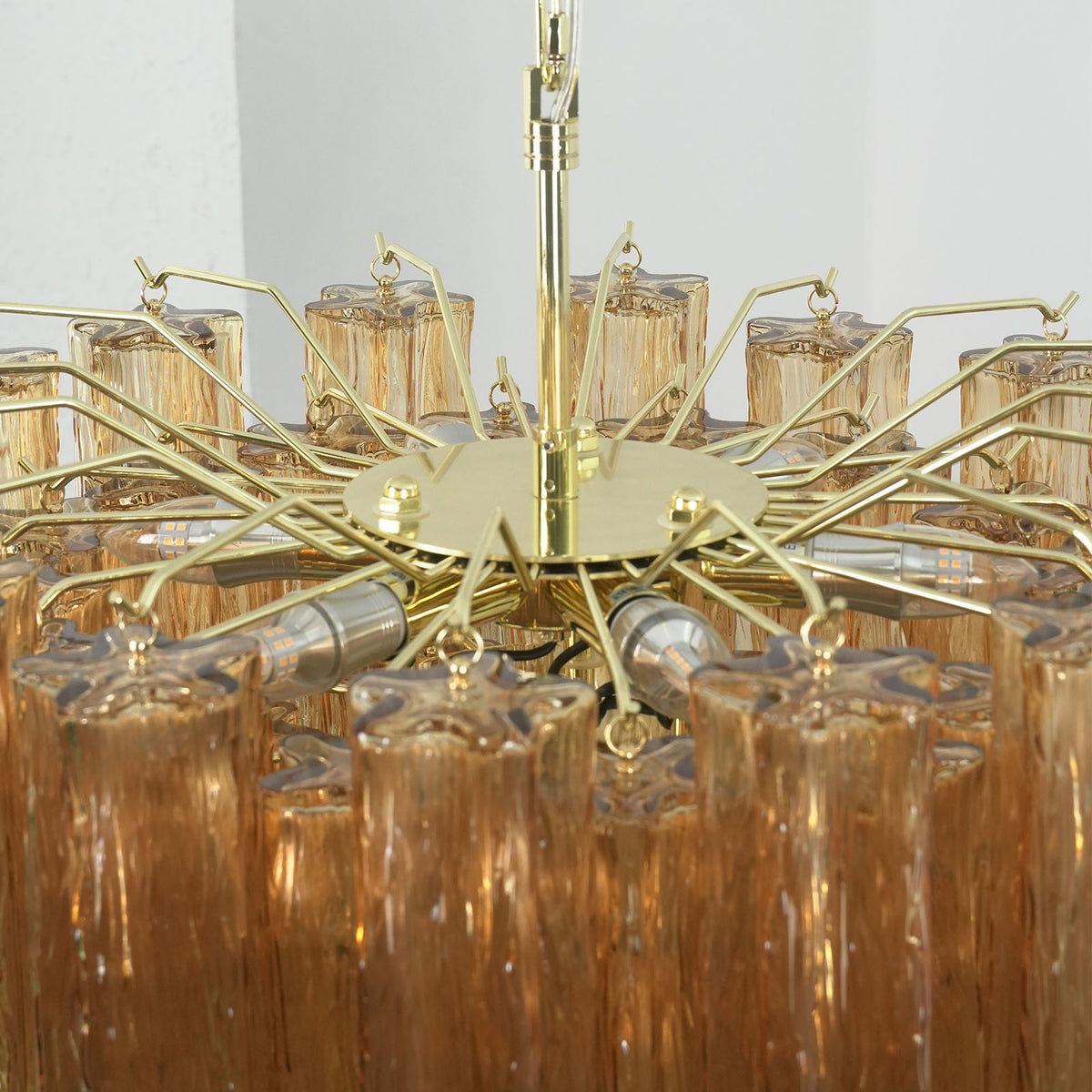 Merlande Amber Glass Tube Tiered Chandelier | Fluted Amber Glass and Brass | Top-down angled view showing the circular brass frame wheel structure | Severn Lighting
