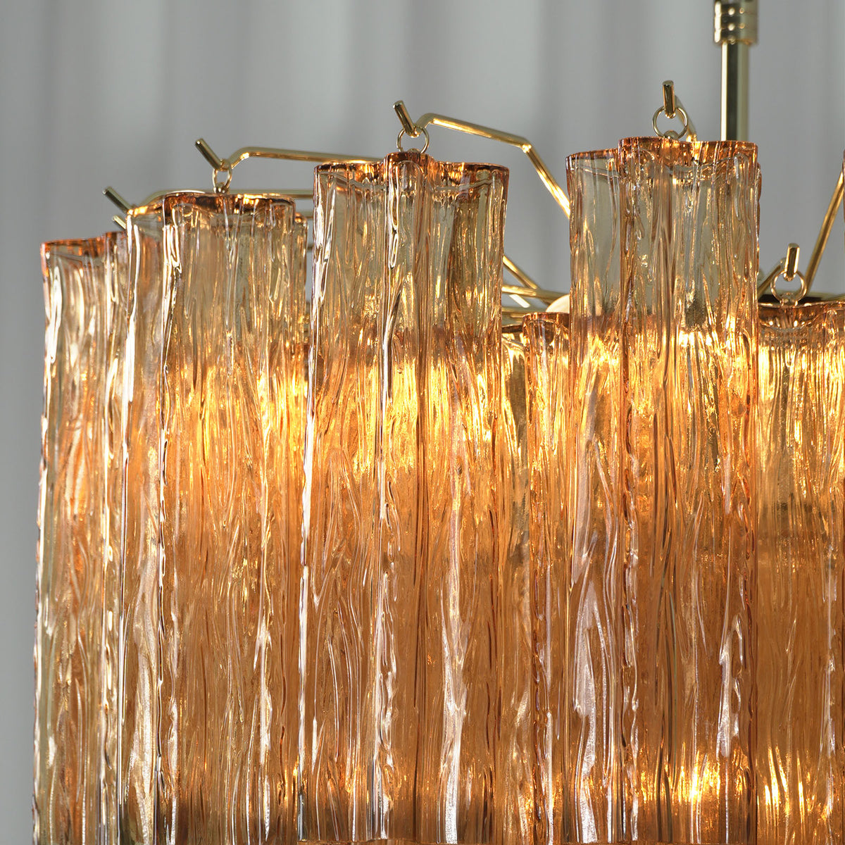 Merlande Amber Glass Tube Tiered Chandelier | Fluted Amber Glass and Brass | Close-up detail of top brass frame hooks and fluted amber glass tubes | Severn Lighting