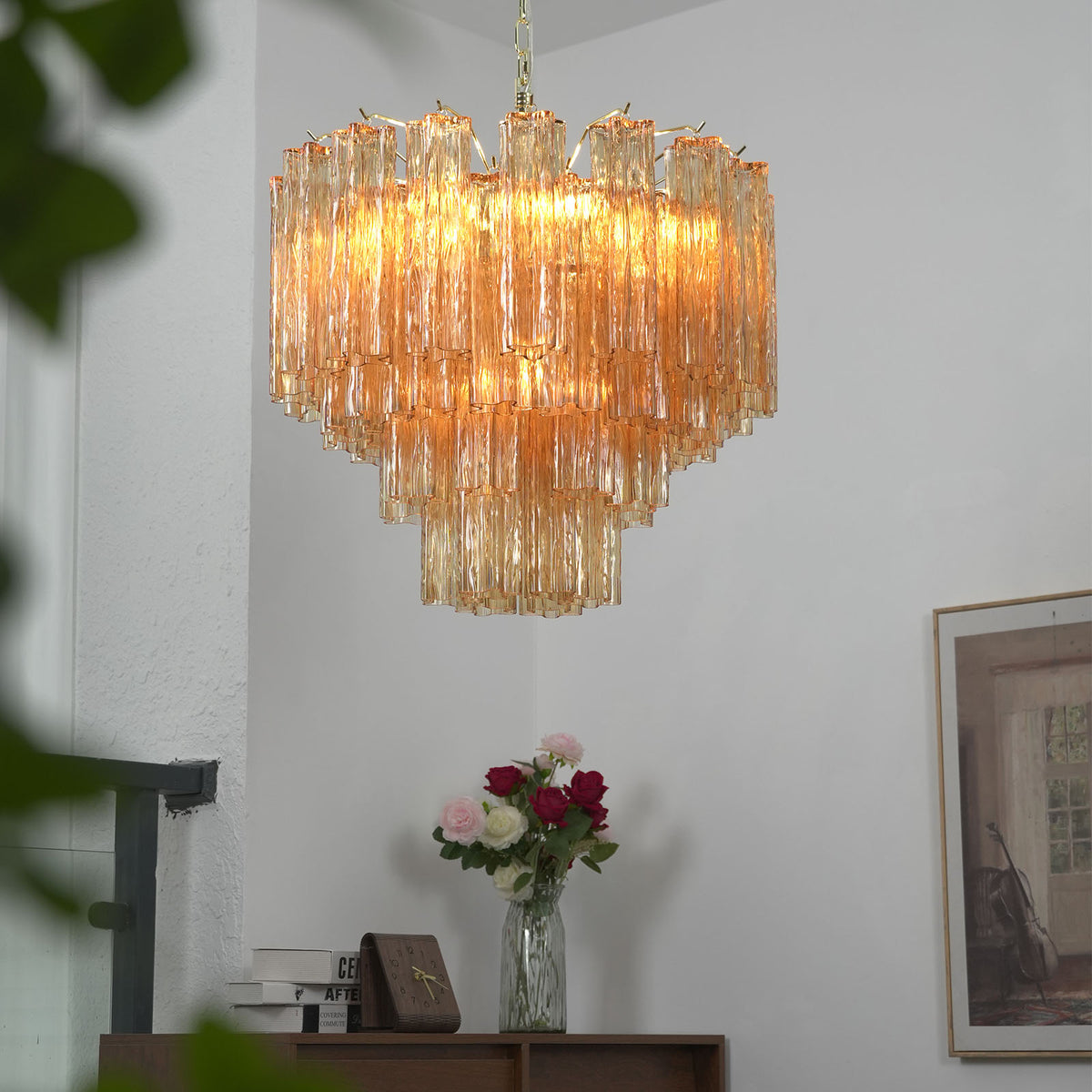Merlande Amber Glass Tube Tiered Chandelier | Fluted Amber Glass and Brass | Real-life view hanging near a staircase and wooden cabinet with flower vase | Severn Lighting