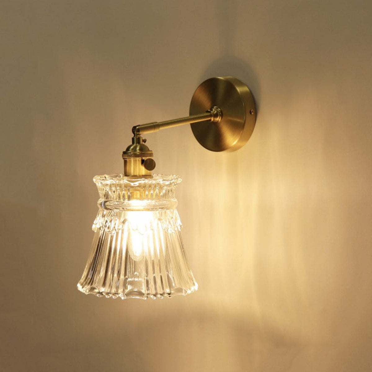Merrick Fluted Glass Bell Wall Lamp | Fluted Glass and Brass | Illuminated sconce casting warm light against a dark wall backdrop | Severn Lighting