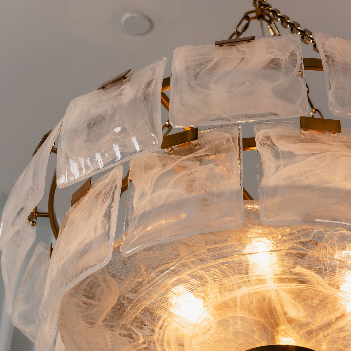 Nyle Tiered Glass Ring Chandelier | Textured Glass and Brass | Close-up angled view of layered translucent glass panels and brass ring | Severn Lighting