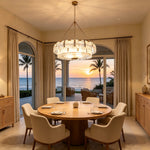 Nyle Tiered Glass Ring Chandelier | Textured Glass and Brass | Illuminating a round table dining area with ocean sunset views | Severn Lighting