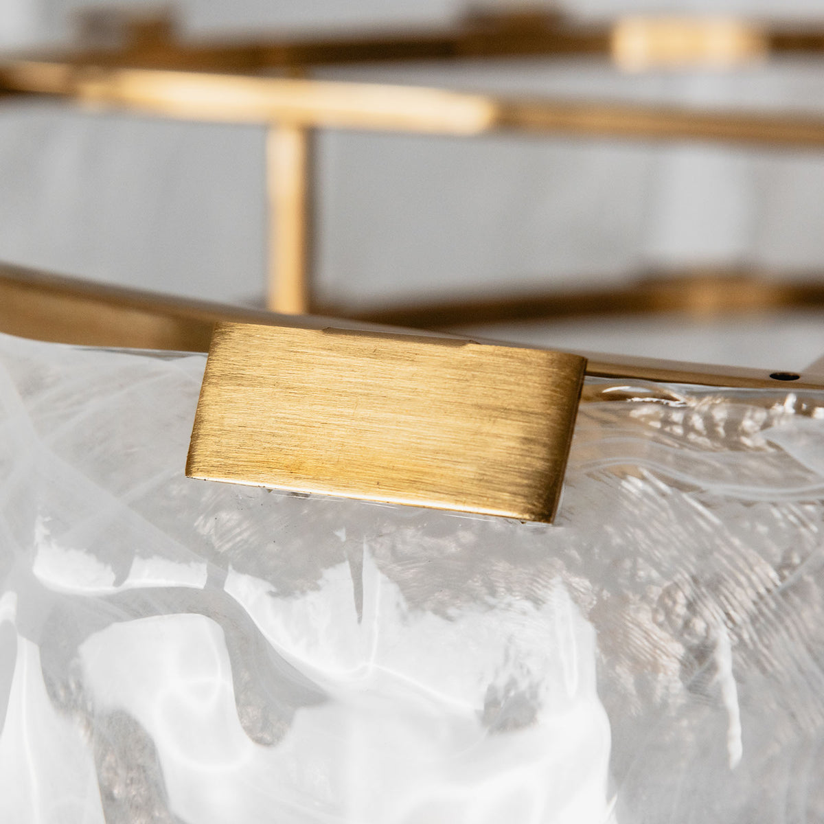 Nyle Tiered Glass Ring Chandelier | Textured Glass and Brass | Close-up detail of the brushed brass clip securing a textured glass panel | Severn Lighting