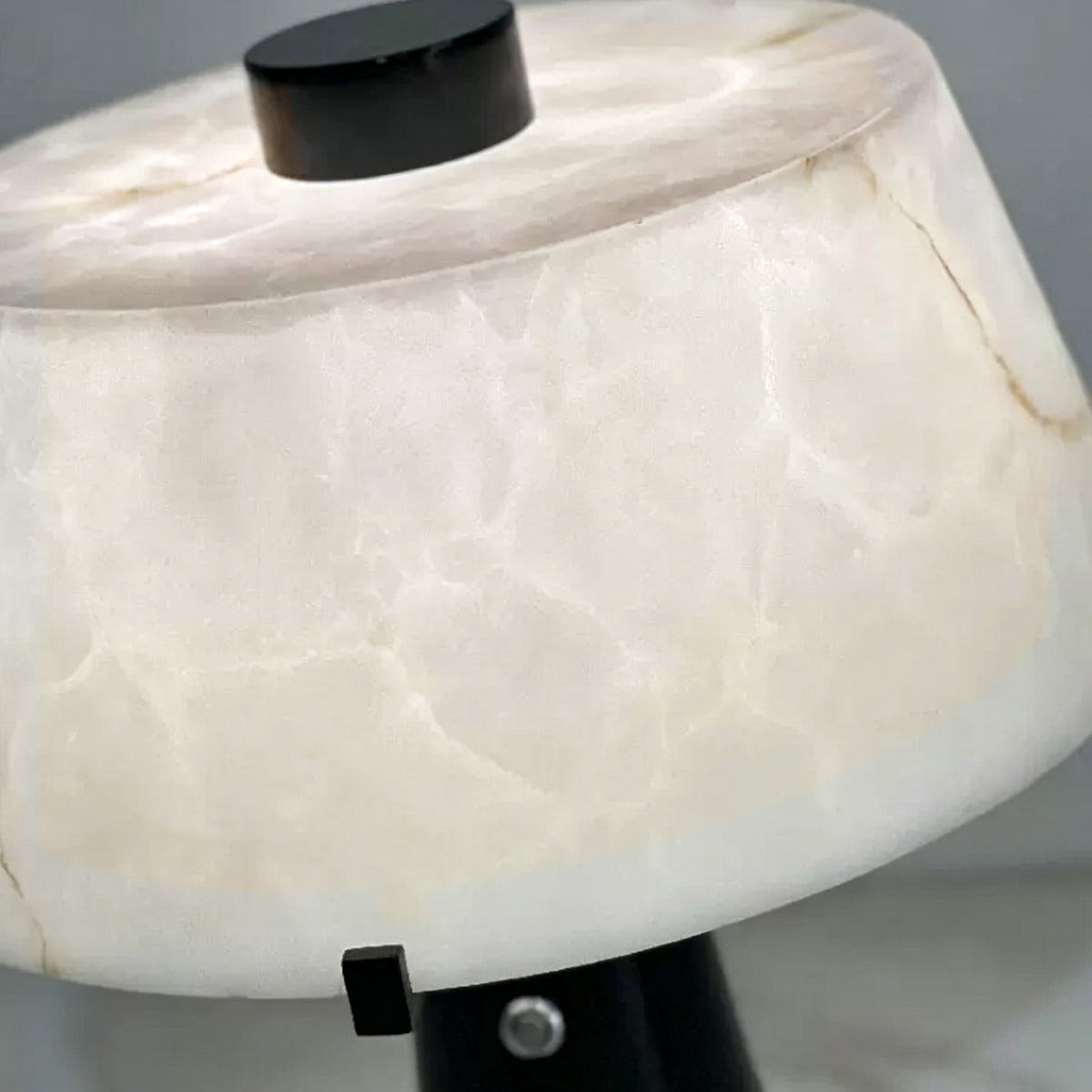 Orsino Alabaster Trapezoid Table Lamp | Natural Alabaster, Black Metal and Brass | Close-up of the illuminated trapezoid alabaster shade showing natural stone veins | Severn Lighting