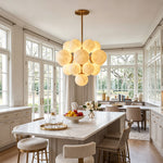 Ottoline Alabaster Cluster Chandelier | Natural Alabaster and Brass | Hanging beautifully over a white marble dining table in a bright grand room with French doors | Severn Lighting