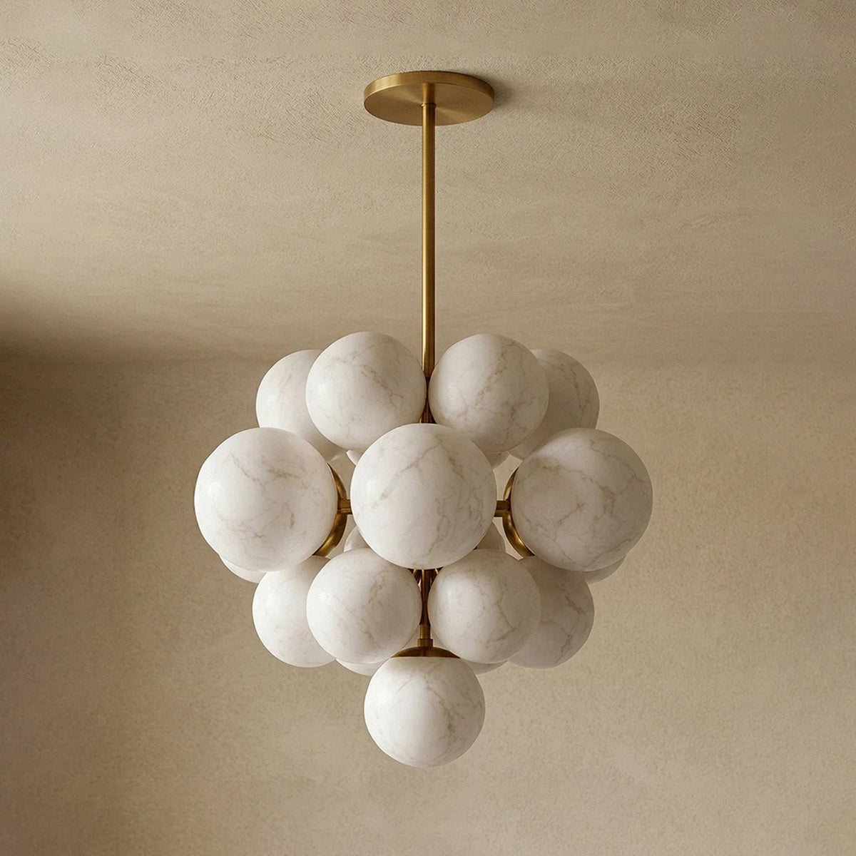 Ottoline Alabaster Cluster Chandelier | Natural Alabaster and Brass | Standard product display hanging against a textured beige backdrop with spheres subtly illuminated | Severn Lighting