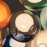 Rainbow Glass Bubble Cluster Chandelier | Multi-colored Blown Glass and Metal Cords | Macro close-up shot focusing on an illuminated dark translucent grey glass sphere with an inner bulb | Severn Lighting