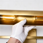 Redmond Brass Picture Wall Lamp | Brass and Metal | Gloved hand adjusting the cylindrical brass light bar mechanism | Severn Lighting